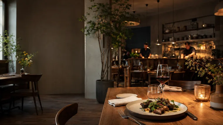 Gedeckter Restauranttisch mit Weinglas am Abend (Konzeptstudie Tisch & Teller)
